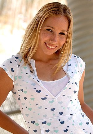 Denim-wearing blonde cracks a smile while teasing you outdoors